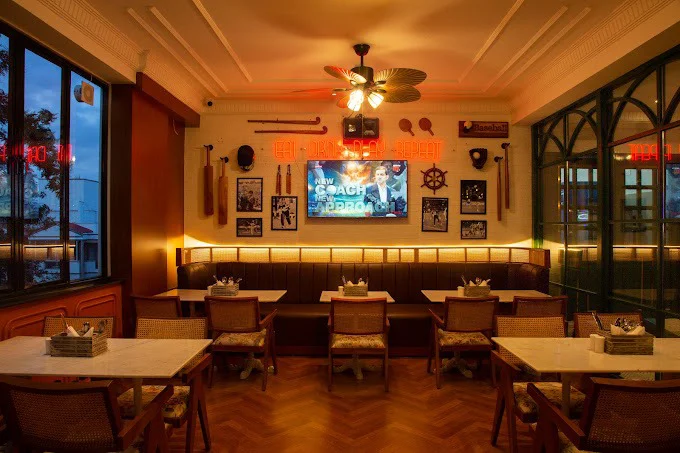 The cozy corner booth with a TV screen and sports memorabilia on the wall at The Studs, a hospitality project in Bangalore.
