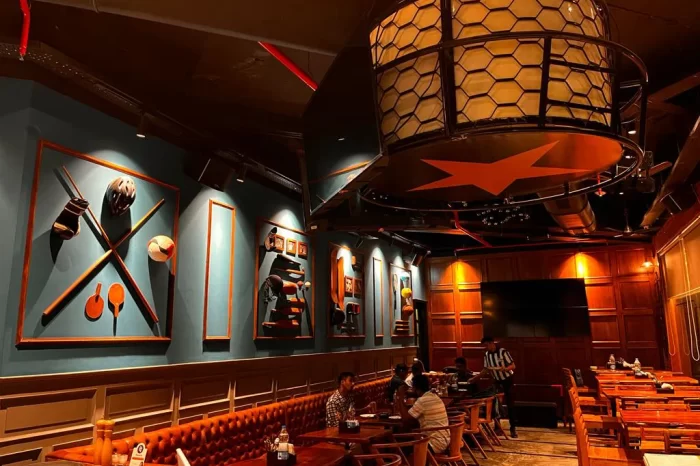 The main dining area of The Studs sports bar in Vashi, showcasing the unique star-shaped light fixture and custom sports-themed wall art.