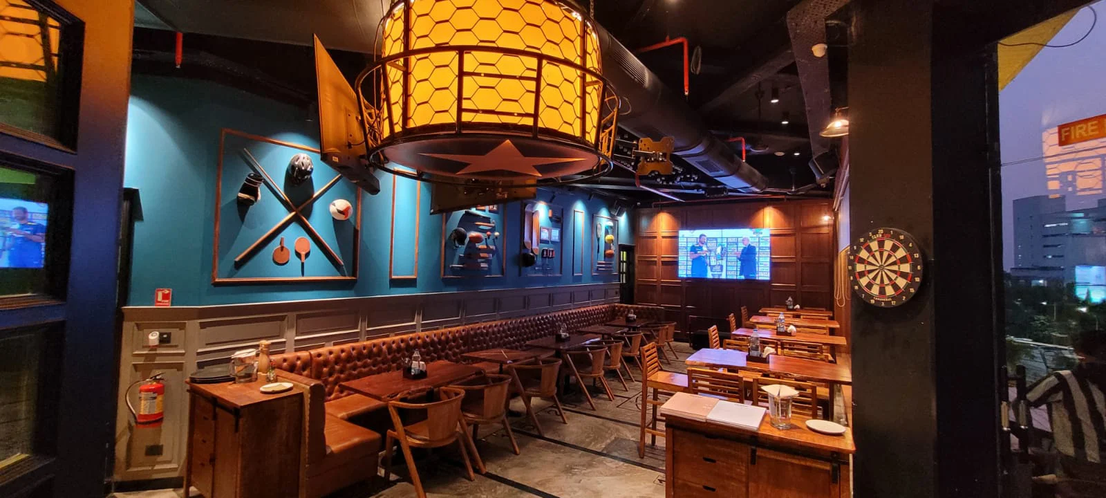 A panoramic view of the 1550 sq. ft. interior of The Studs in Vashi, featuring extensive leather booth seating and sports-themed wall decor.