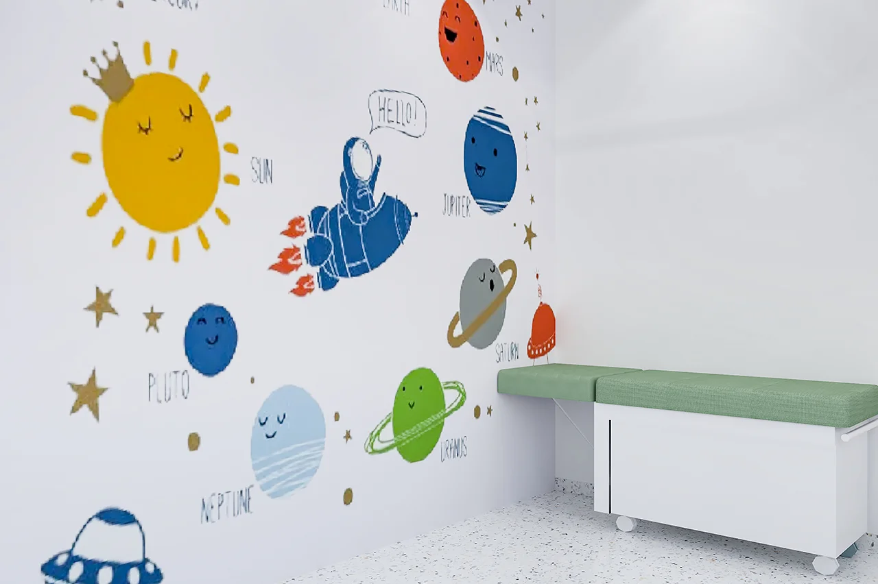 Pediatric treatment room with a playful space-themed wall mural (planets, sun, astronaut) and white exam couch.